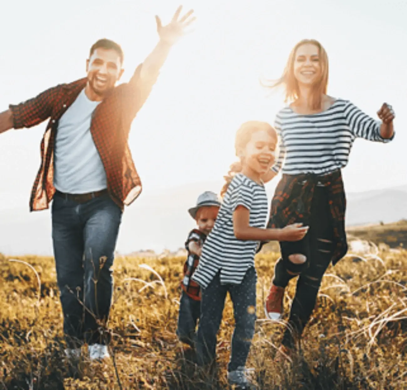 Fotografía de una mujer, un hombre, una niña y un niño. Los cuatro sonríen mientras corren hacia la cámara.
